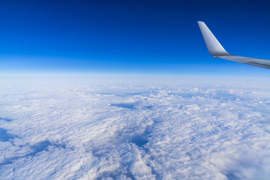 飛行機の機内から窓越しに見える青空と翼