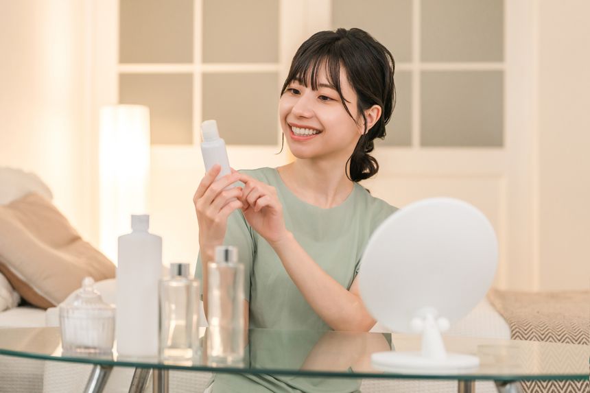 鏡の前でスキンケアアイテムを手に取る女性