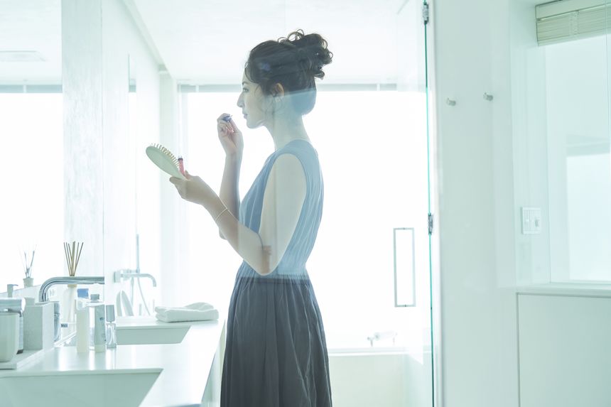 洗面台でスキンケアアイテムを手に取る女性の手元