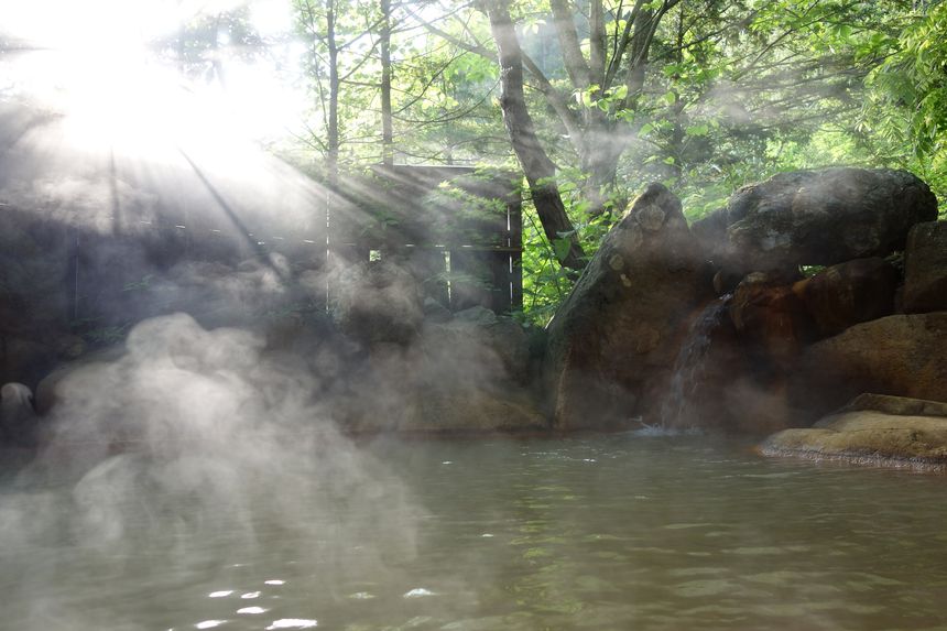 朝の光が差し込む露天風呂と湯けむり